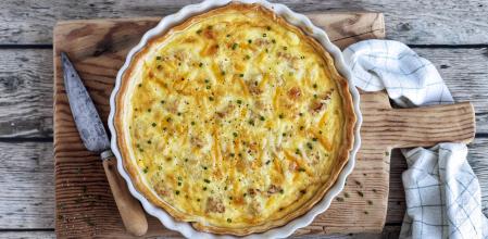 Quiche de coliflor sobre una tabla de madera con un cuchillo