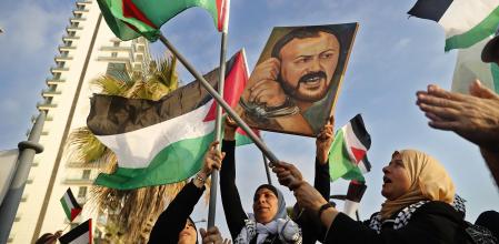 FILE - Palestinian women shout slogans while waving their national flags with a picture of jailed leader Marwan Barghouti, during a protest in Beirut, Lebanon, on May 4, 2017. Hamas officials say that any cease-fire deal with Israel should include the release of prisoner Marwan Barghouti — a leader of the militant group's main political rival. The demand by Hamas marks the central role Barghouti plays in Palestinian politics — even after more than two decades behind bars and sentenced by Israel to multiple life terms in prison. (AP Photo/Hussein Malla, File)