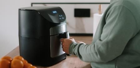 Una persona cocinando con una freidora de aire.