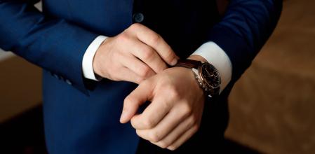 Un hombre vestido de traje poniéndose un reloj.