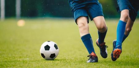 Dos jugadores corriendo detrás de un balón de fútbol.