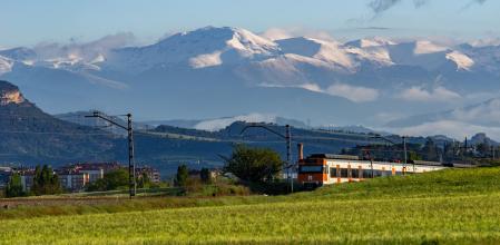 El tren de la línea R3 en la Plana de Vic con el Pirineo nevado de fondo.