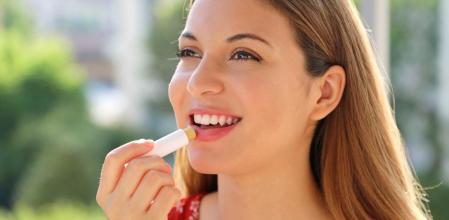 Una mujer aplicándose un labial hidratante.