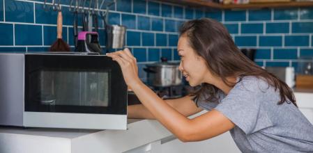 Una mujer usando su microondas.