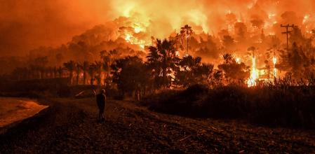(FILES) A man stands in front of a wild fire in Schinos, west of Athens, on May 19, 2021. Led by the United Nations Environment Programme (UNEP) since 1973, World Environment Day 2024 will take place on June 5, 2024. (Photo by VALERIE GACHE / AFP)