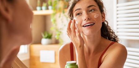 Una mujer haciendo su rutina de limpieza y cuidado facial.