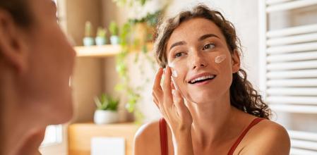 Una mujer haciendo su rutina de limpieza y cuidado facial.