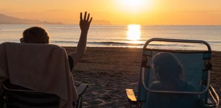 Una pareja en sillas de playa viendo la puesta de sol