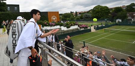 Spain's Carlos Alcaraz throws balls to wainting fans after taking part in a training session on the eve of his men's final tennis match, at the Aorangi Practice Courts, on the thirteenth day of the 2024 Wimbledon Championships at The All England Lawn Tennis and Croquet Club in Wimbledon, southwest London, on July 13, 2024. Alcaraz will face Serbia's Novak Djokovic in the men's final on July 14. (Photo by ANDREJ ISAKOVIC / AFP) / RESTRICTED TO EDITORIAL USE
