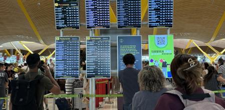 Pasajeros en el aeropuerto de Barajas frente a los paneles de salidas&nbsp;