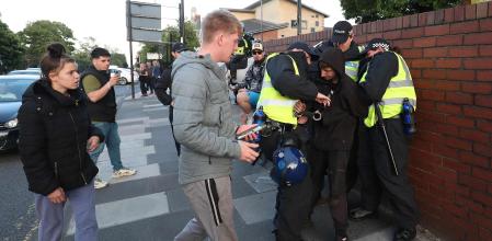 Police officers detain a person for shouting racist comments during a counter demonstration against an anti-immigration protest called by far-right activists, near the United Immigration Services offices at The Beacon in Newcastle-upon-Tyne, north-east England on August 7, 2024. Thousands of riot police stood ready Wednesday as Britain remained on alert for disturbances during far-right protests across the country. Nightly riots, during which mosques and migrant targets have been attacked, erupted after three children were murdered in Southport on July 29. (Photo by SCOTT HEPPELL / AFP)