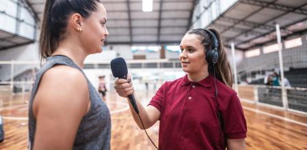 Una joven periodista deportiva entrevistando a una jugadora de baloncesto.