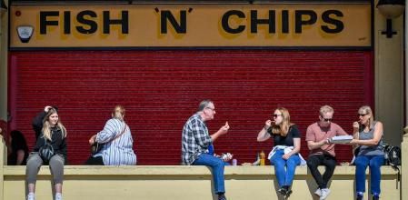 People eat fish and chips at Barry Island, Wales. (Photo by Ben Birchall/PA Images via Getty Images)