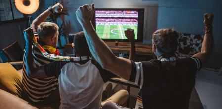 Un grupo de amigos viendo el fútbol en la televisión.