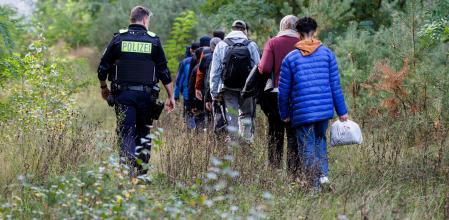 (FILES) An officer of the German Federal Police (Bundespolizei) escorts a group of migrants near Forst, eastern Germany on October 11, 2023, during a patrol near the border with Poland. Germany will extend temporary controls to all of its borders to crack down on irregular migration into the country, a government source told AFP on September 9, 2024. (Photo by JENS SCHLUETER / AFP)