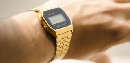 Un reloj dorado estilo Casio en la muñeca de un hombre