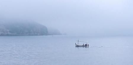 Barca navegando entre la niebla junto a las Islas Medas.