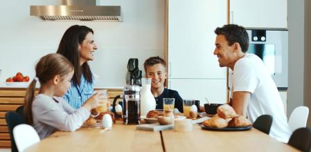 Una familia feliz desayunando en la cocina de su casa.