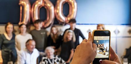 Family posing with grandmother celebrating the 100 year birthday during a lunch celebration.