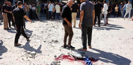 Desplazados palestinos observando rastros de sangre en el campo de refugiados de Shati