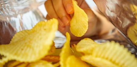 Hand hold potato chips inside snack foil bag