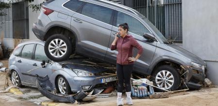 Una vecina habla por teléfono junto a dos coches destrozados este sábado, en Paiporta, Valencia, tras el paso de la DANA&nbsp;