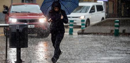 Una mujer camina con su paraguas en la avenida Meridiana de Barcelona.