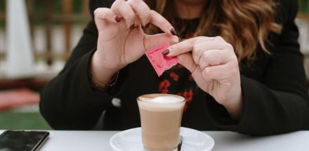 A young woman having a coffee wearing a protective face mask