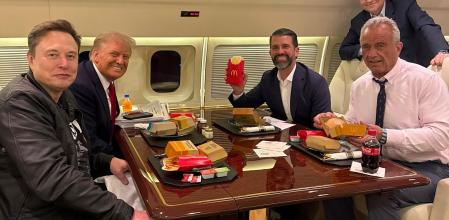 Elon Musk, Donald Trump, Donald Trump JR, el próximo secretario de Salud, Robert F. Kennedy y, de pie, el portavoz, Mike Johnson, en un avión privado ante comida de McDonalds