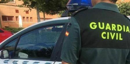 Imagen de archivo de un agente de la Guardia Civil ante un coche patrulla
