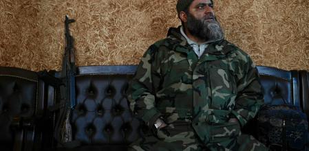 A Syrian rebel fighter sits in a 'Management of Liberated Areas' authority office in Maaret al-Numan, in the northwestern Syrian Idlib province, on December 14, 2024. Vegetation grows between crumbled walls and torn asphalt in Maaret al-Numan, once home to nearly 100,000 people, which became a key battleground since fighting broke out in the Syrian civil war in 2012 due to its location on the strategic M5 highway linking Aleppo to Damascus. But with the ousting of long-time president Bashar al-Assad on December 8 by an Islamist-led rebel force, many of its residents displaced by war couldn't stay away after years of exile, and are returning, eager to rebuild their homes and lives in spite of the surrounding devastation. (Photo by Ozan KOSE / AFP)