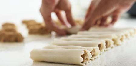closeup of a caucasian man preparing some meat stuffed cannelloni on the countertop of a kitchen