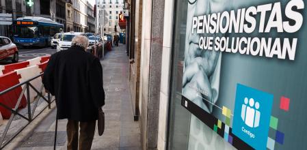 Jubilado por calle de madrid con cartel de Publicidad sobre pensionistas