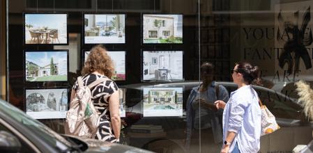 Dos personas observan los anuncios de viviendas en venta en una inmobiliaria, a 15 de abril de 2024, en Palma de Mallorca, Mallorca, Baleares (España). El pasado 16 de abril, el Pleno del Parlament de las Illes Balears aprobó una Ley, proveniente del Decreto Ley 6/2023, de 2 de octubre, de medidas urgentes en materia de vivienda, con la que ha introducido medidas para favorecer la salida al mercado de nuevas viviendas en las áreas urbanas de los municipios de las Islas Baleares. El Colegio Oficial de Agentes de la Propiedad Inmobiliaria de Baleares (COAPI) y la alianza de inmobiliarias Balears ABINI han celebrado la aprobación.