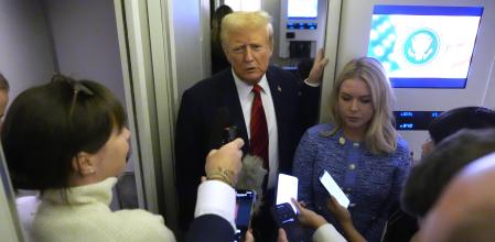 President Donald Trump speaks to reporters aboard Air Force One en route from Miami to Joint Base Andrews, Md., Monday, Jan. 27, 2025, as White House press secretary Karoline Leavitt listens. (AP Photo/Mark Schiefelbein)