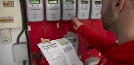 Un hombre comprueba su factura de la luz junto a los contadores de su comunidad de vecinos