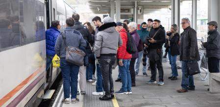 Passatgers pujant i baixant dels trens ,gent esperan a les andanes.