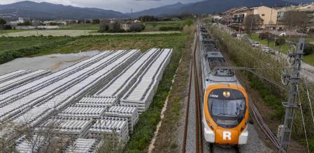 Un tren de Rodalies, circulando por la vía única de la R3, junto al material para la futura obra