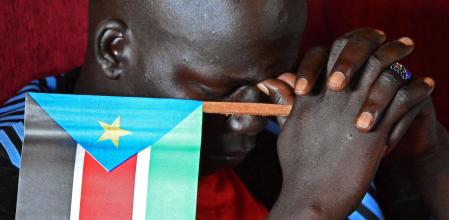 Un hombre sostiene una bandera de Sudán del Sur, país nacido en el año 2011 con un economía precaria