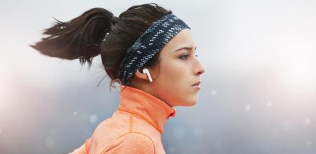 Una mujer corriendo con auriculares inalámbricos