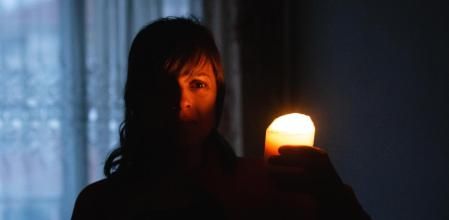 Mujer acompañada de una vela durante un apagón 