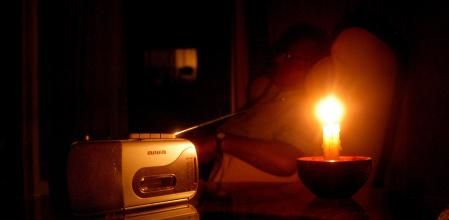Un jubilado con radio y velas tras quedarse sin luz por el apagón eléctrico de abril. 