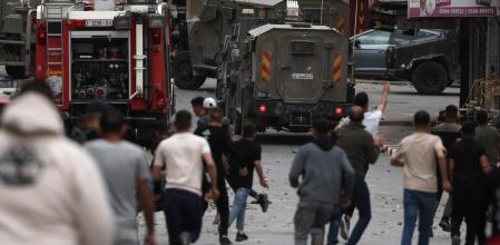 Palestinos lanzan piedras contra vehículos militares israelíes durante los enfrentamientos tras una incursión del ejército israelí en la ciudad cisjordana de Naplusa&nbsp;