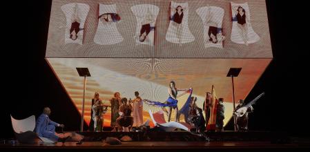 Julie Fuchs (Cleopatra) seduciendo a Xavier Sabata (Julio César, a la izquierda) rodeada de una troupe musical que es parte del montaje