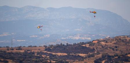 Helicópteros de bomberos tratan de apagar los restos del incendio, a 2 de julio de 2025, en Torrefeta i Florejacs, Lleida, Catalunya (España). Dos personas han muerto en el incendio declarado este martes por la tarde en Torrefeta i Florejacs, en la comarca de la Segarra (Lleida). Los bomberos encontraron los cadáveres cuando hacían tareas de extinción dentro del perímetro del incendio, cerca del núcleo de Coscó, y los Mossos investigan las circunstancias del siniestro. El fuego ha arrasado 1.830 hectáreas según Agents Rurals.