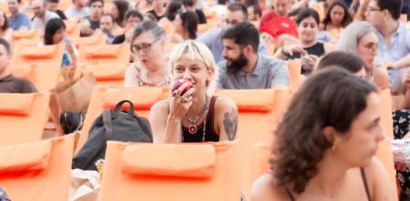 Una de las asistentes del cine al aire libre de Barcelona en el Parque de Montjuic disfrutando del sabor de las manzanas 'Cosmic Crisp'&nbsp;