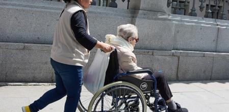 Una mujer mayor en silla de ruedas y su cuidadora