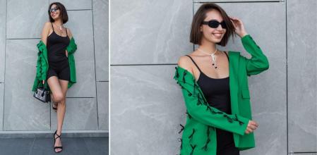 Una chica con un mono deportivo negro y una blazer verde, una combinación que está de moda