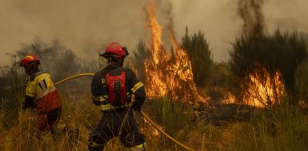 Vecinos y bomberos intentan aplacar el fuego que afecta este viernes a la aldea de Lamas (Cualedro), en Ourense.
