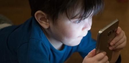 Un niño ante la pantalla de un teléfono móvil.
